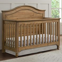 a wooden baby crib in a room with hardwood floors and white walls, along with a rug on the floor