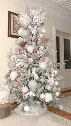 a white christmas tree with pink and silver ornaments