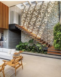 a living room filled with furniture next to a stair case covered in plants and rocks