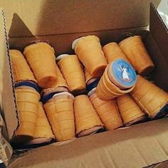 an open cardboard box filled with lots of ice cream cones and wrapped in brown paper