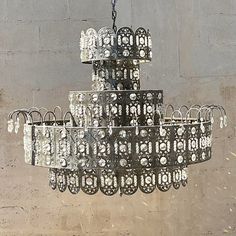 a large chandelier hanging from the ceiling in front of a concrete wall,