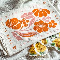 two napkins with flowers on them sitting on a lace tablecloth