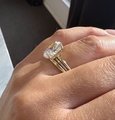 a woman's hand holding a ring with a diamond on it and two bands around the band