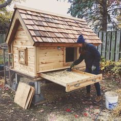 a man is building a chicken coop in the yard with his hands on the roof