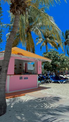 a pink and white building sitting on top of a sandy beach next to palm trees