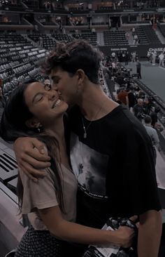 two people standing next to each other in front of a crowd at a tennis match