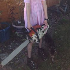 a woman in pink dress holding a chainsaw and a dog standing next to her