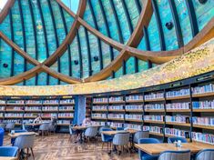 the inside of a library with tables, chairs and bookshelves full of books