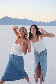 two women standing in the snow with their hands up