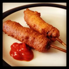 two chicken skewers with ketchup on a white plate