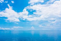 the sky is filled with clouds and blue water as seen from a boat in the ocean