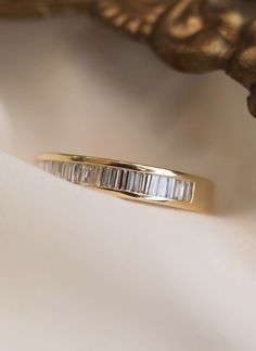 a gold ring with three baguets on it sitting on top of a white cloth