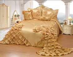 a large bed covered in golden ruffled sheets