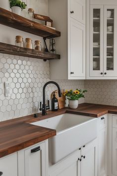 a kitchen with white cabinets and wooden counter tops, an open shelving above the sink