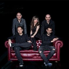 a group of people sitting on top of a red couch in front of a black background