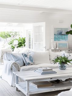 a living room filled with white furniture and plants