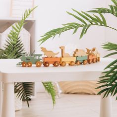 a toy train is sitting on a table next to a potted palm tree in the corner