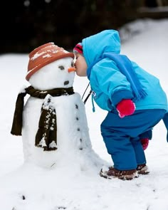 a small child playing with a snowman in the snow