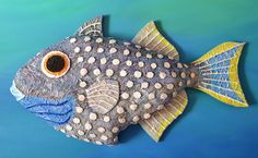 a decorative fish made out of paper on a blue surface with white dots and black spots