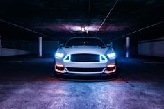 a white sports car parked in a parking garage with its headlight turned on at night