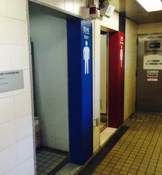 an empty bathroom with blue and red stalls next to each other on the wall,