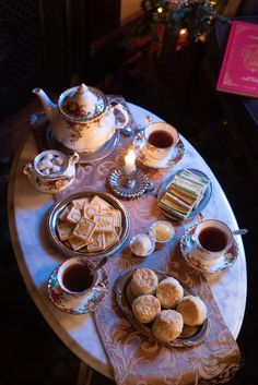 a table topped with plates and cups filled with food next to a tea pot on top of a table