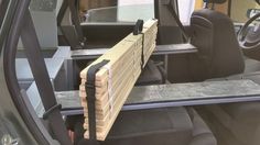 the interior of a small vehicle with wood pieces in the back seat and seats folded down