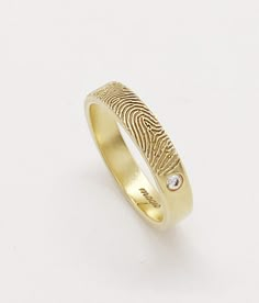 a gold fingerprint ring with a diamond in the center