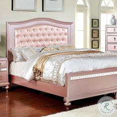 a pink bed sitting on top of a wooden floor next to a dresser and mirror