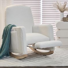 a white rocking chair sitting on top of a rug