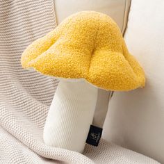 a yellow mushroom pillow sitting on top of a white couch next to a pair of socks