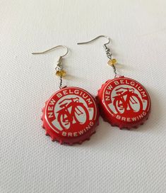 red bottle cap earrings with white bicycle logo on them, hanging from silver earwires