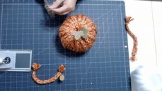 someone is making a pumpkin out of yarn on a cutting board with scissors and tape