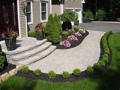 a driveway with landscaping and steps leading up to the house