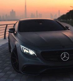 the front end of a black mercedes benz coupe parked in front of a city skyline