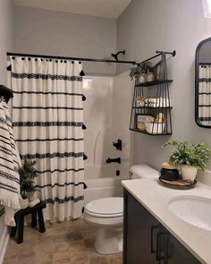 a bathroom with a toilet, sink and shower curtain in black and white striped curtains