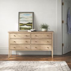 a wooden dresser sitting on top of a hard wood floor next to a white door