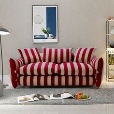 a red and white striped couch sitting on top of a floor next to a lamp