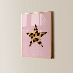 a pink wall with a leopard print star hanging on it's side and a gold frame