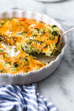 broccoli and cheese casserole in a white dish with a serving spoon