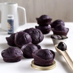 blueberry muffins on a white counter next to a spoon and cupcake tin