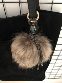 a black purse with a fur ball hanging from it