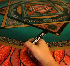 a person is drawing on a large piece of art with black marker and some colored pencils