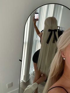 a woman taking a selfie in front of a mirror with her hair styled into a ponytail