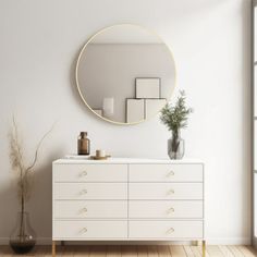 a white dresser with a round mirror above it