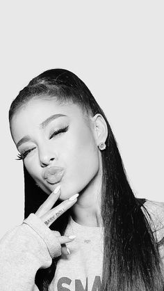 a black and white photo of a woman with long hair blowing out her tongue to the side