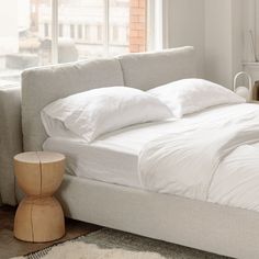 a bed with white sheets and pillows in a bedroom next to a radiator