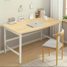 a computer desk with a laptop on top of it next to a chair in front of a window