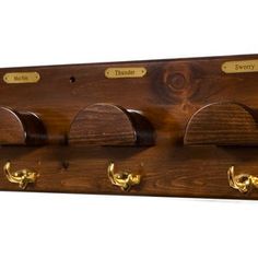 a wooden coat rack with four hooks and three coats hanging on the wall, along with brass knobs