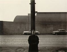 a man standing under a street light next to parked cars